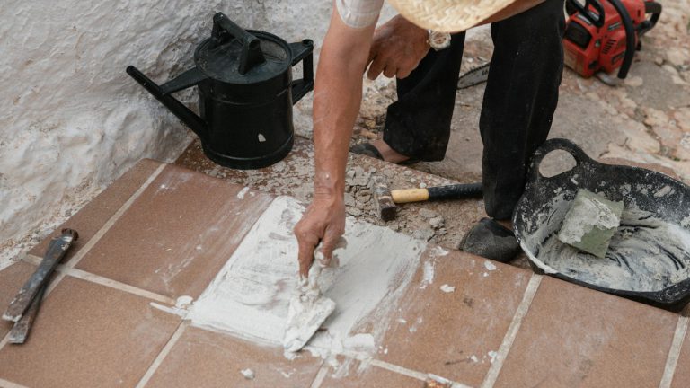 A tiler pressing grout into the joints of floor tiles