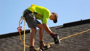 A roofer working on a roof with a power tool