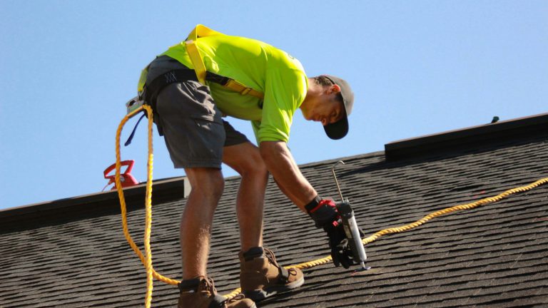 A roofer working on a roof with a power tool