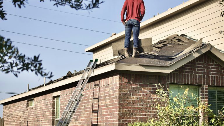A worker standing on the roof of a house