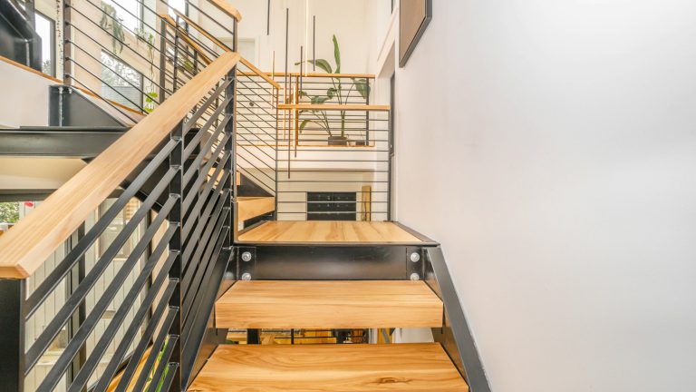 A wooden staircase with stainless steel railings