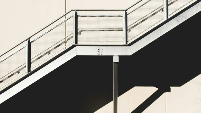 White metal stairs against a concrete wall